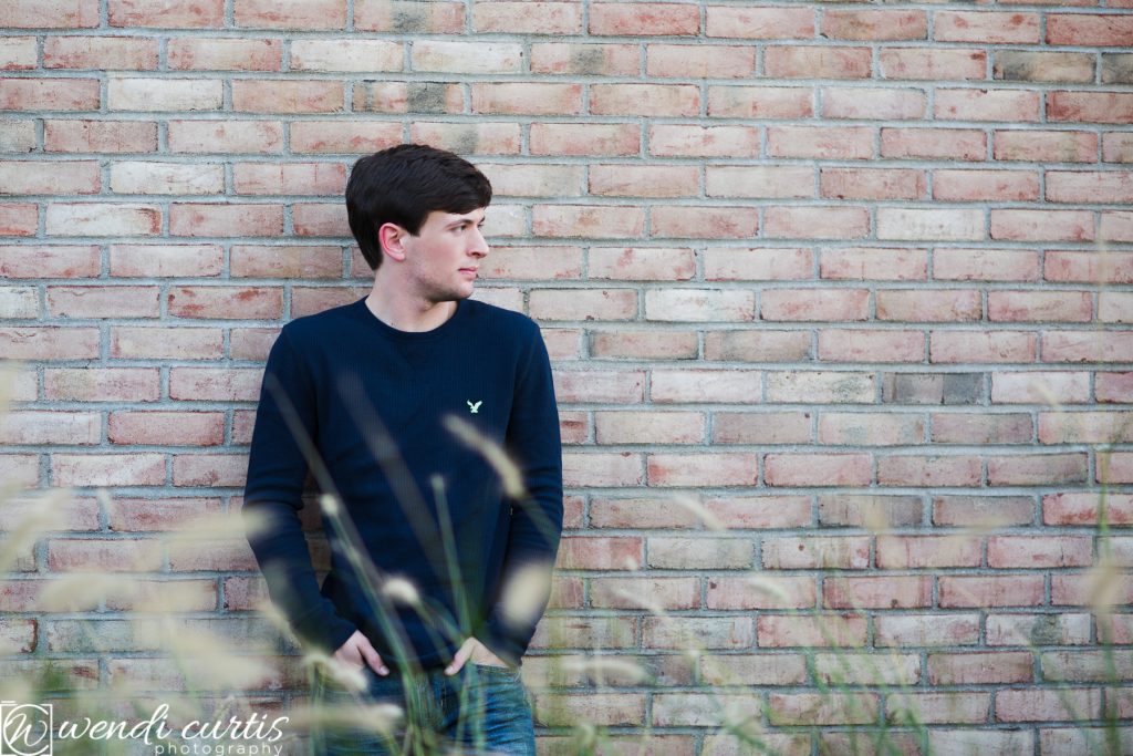senior boy with brick wall